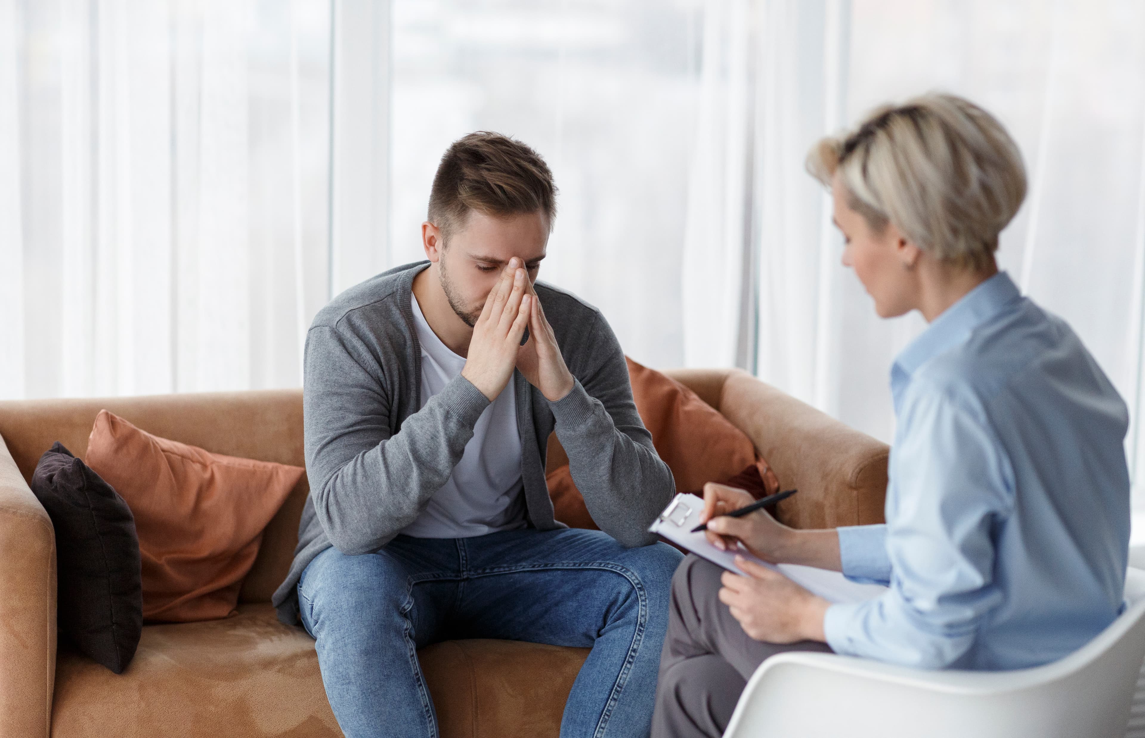 Mann mit Kopf in den Händen im Gespräch mit einer Fachperson